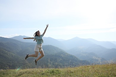 Photo of Sporty young woman jumping on grassy hill in mountains