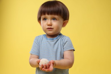 Photo of Cute little child with tasty mochi on yellow background