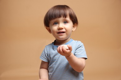 Photo of Cute little child with tasty mochi on light brown background