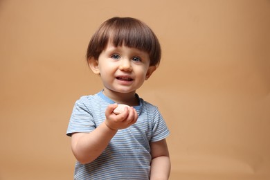 Photo of Cute little child with tasty mochi on light brown background