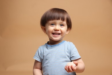 Photo of Cute little child with tasty mochi on light brown background