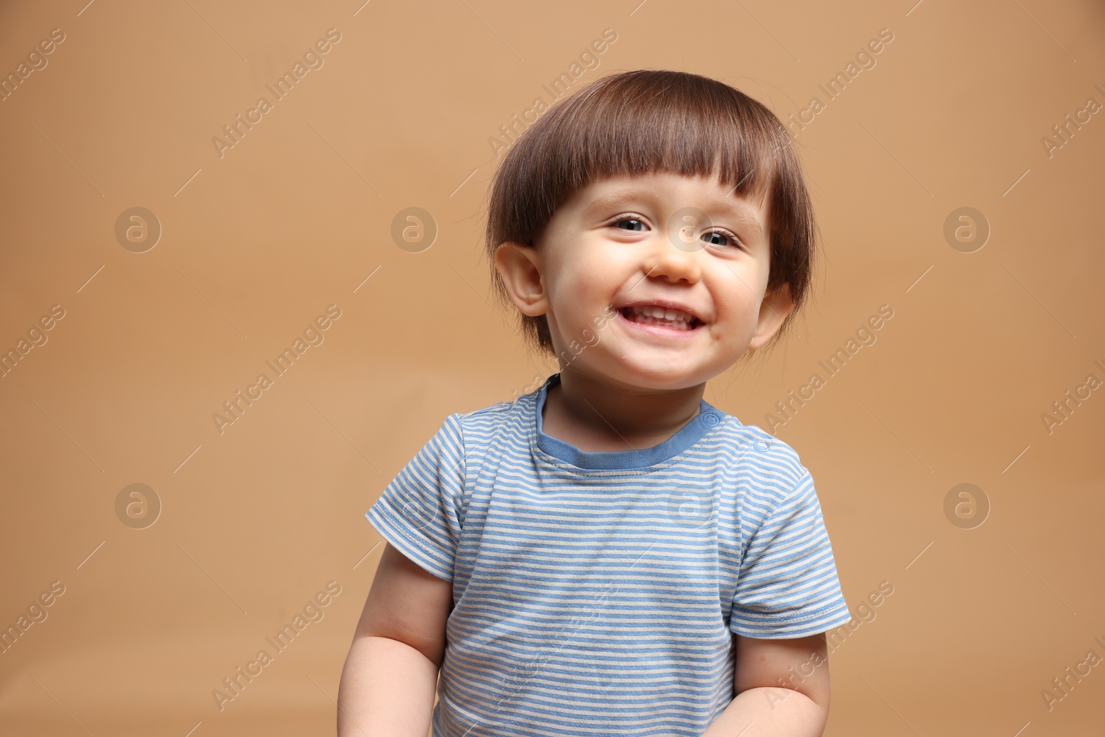 Photo of Portrait of adorable little boy on light brown background