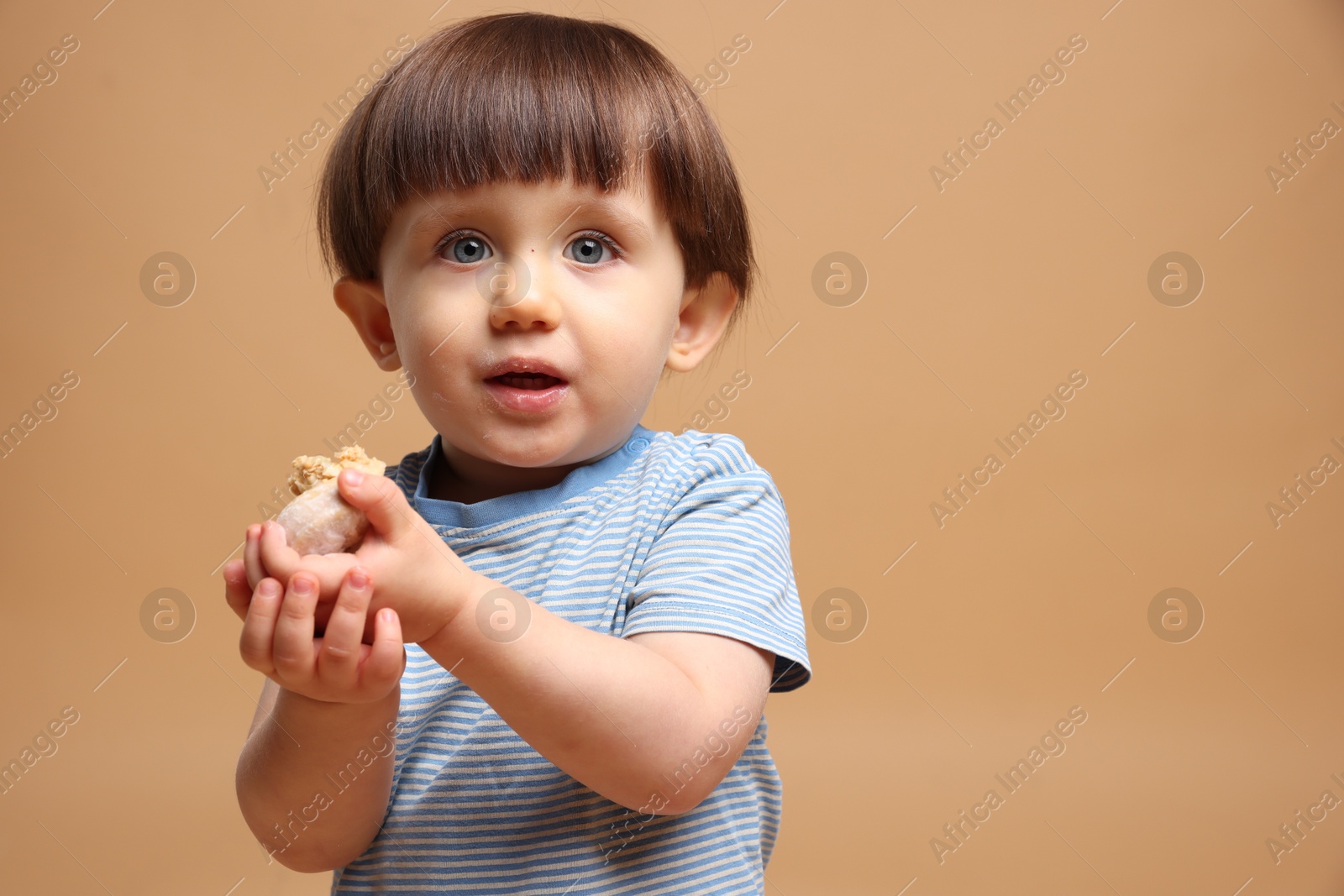 Photo of Cute little child with tasty mochi on light brown background. Space for text