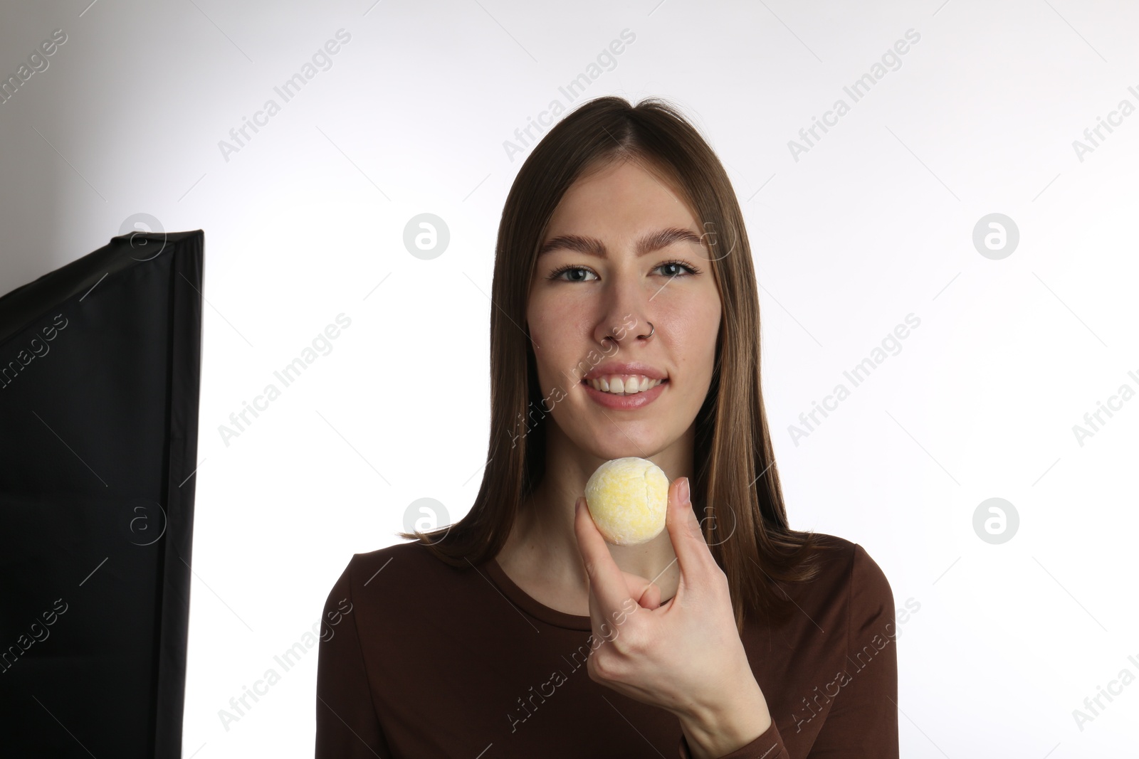 Photo of Smiling woman with tasty mochi on white background