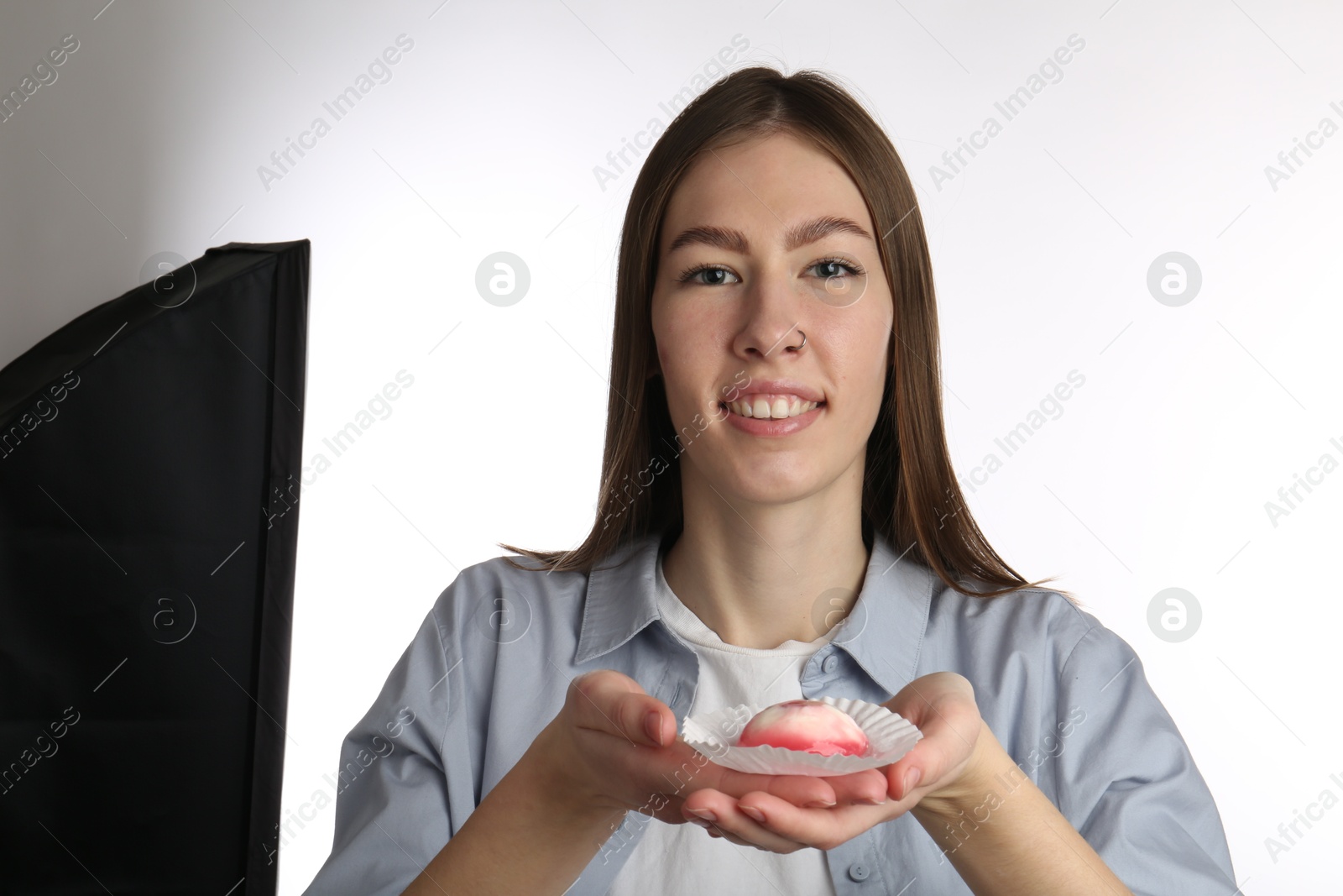 Photo of Smiling woman with tasty mochi on white background