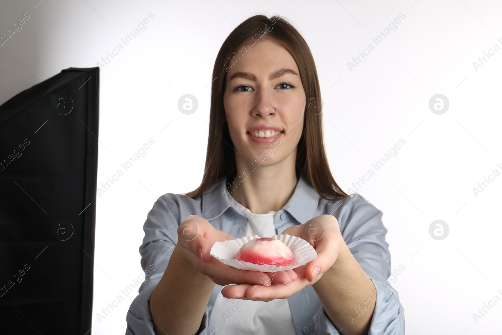 Photo of Smiling woman with tasty mochi on white background