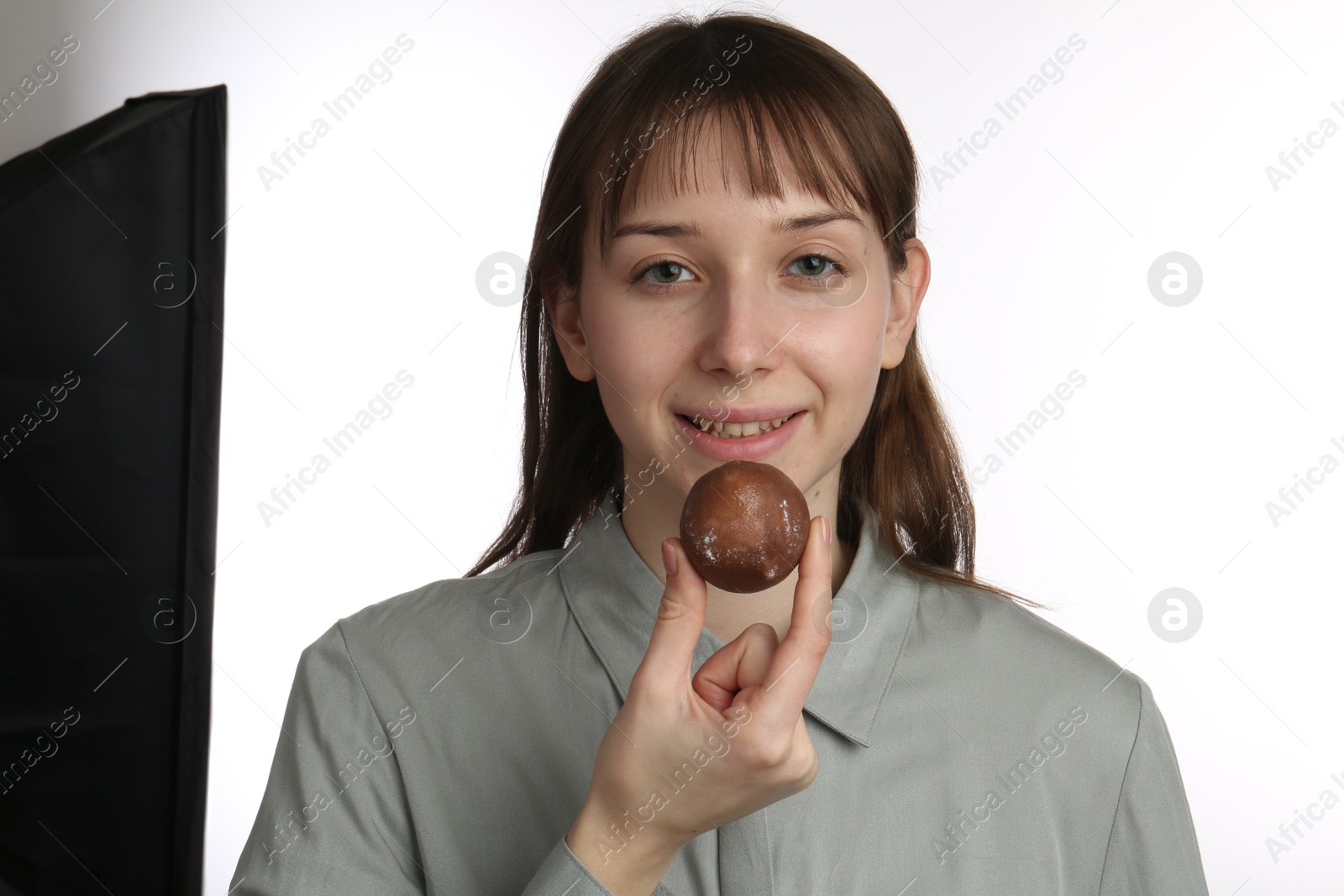 Photo of Happy woman eating tasty mochi on white background