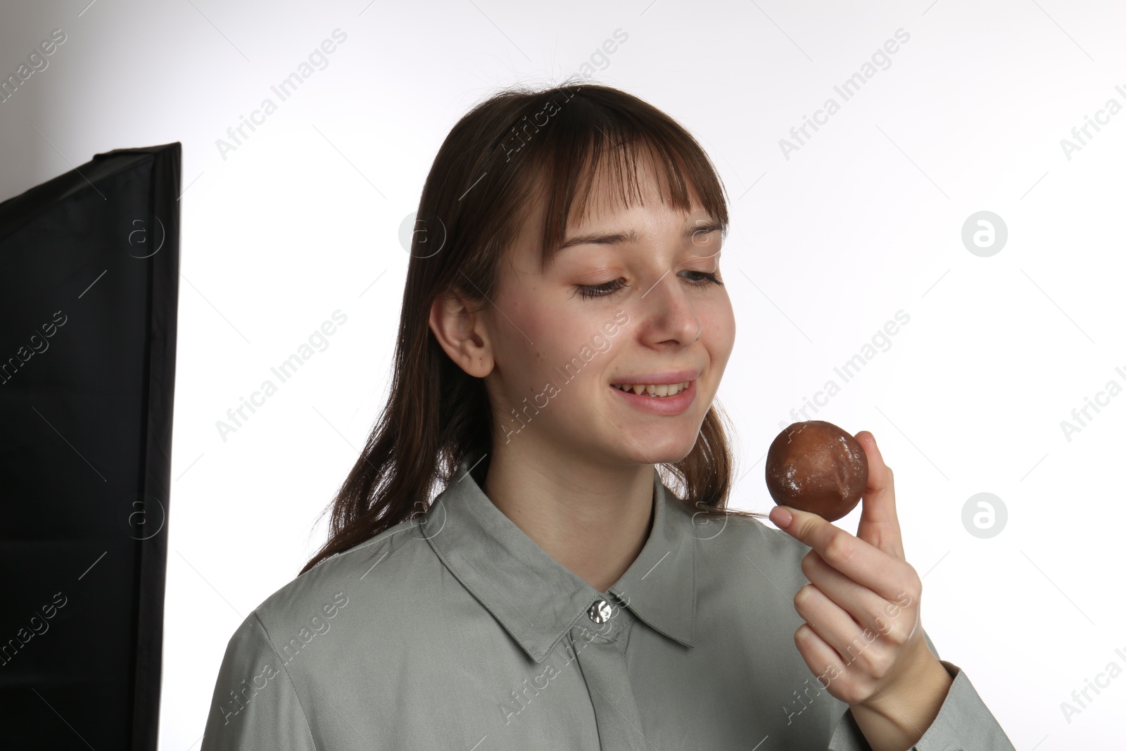 Photo of Happy woman eating tasty mochi on white background