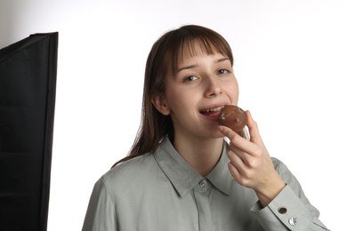 Photo of Happy woman eating tasty mochi on white background