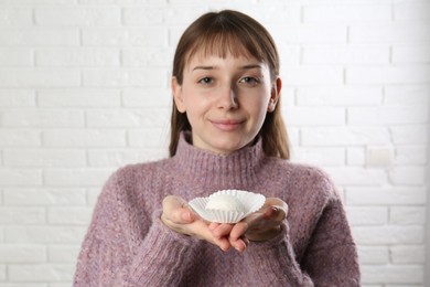 Beautiful woman eating tasty mochi near white wall