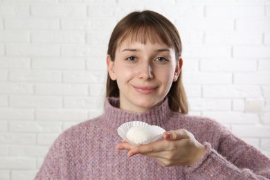 Photo of Beautiful woman eating tasty mochi near white wall