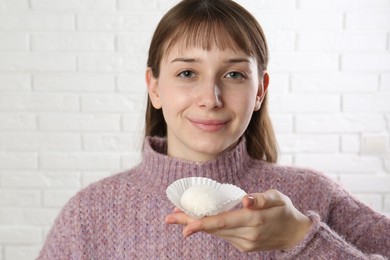 Photo of Beautiful woman eating tasty mochi near white wall