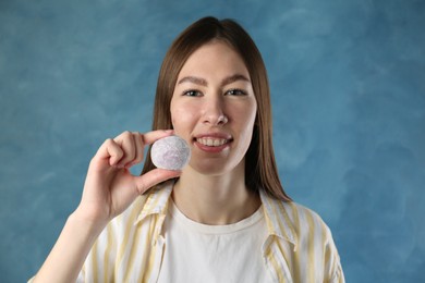 Photo of Smiling woman with tasty mochi on blurred blue background