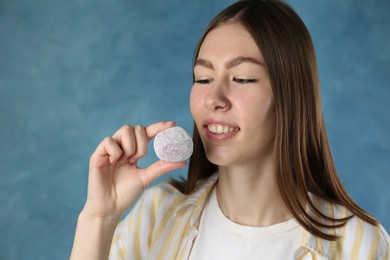 Photo of Smiling woman with tasty mochi on blurred blue background