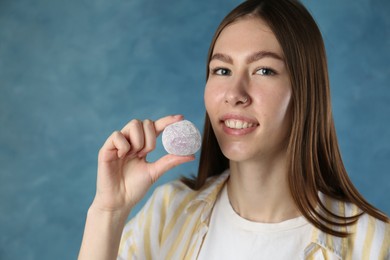 Photo of Smiling woman with tasty mochi on blurred blue background. Space for text