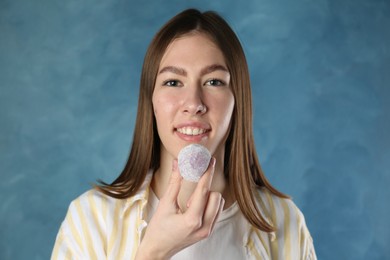 Photo of Smiling woman with tasty mochi on blurred blue background