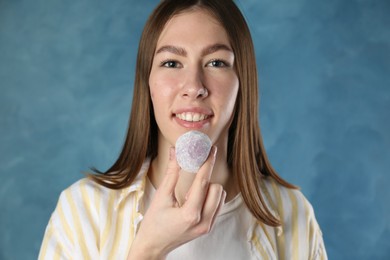 Photo of Smiling woman with tasty mochi on blurred blue background