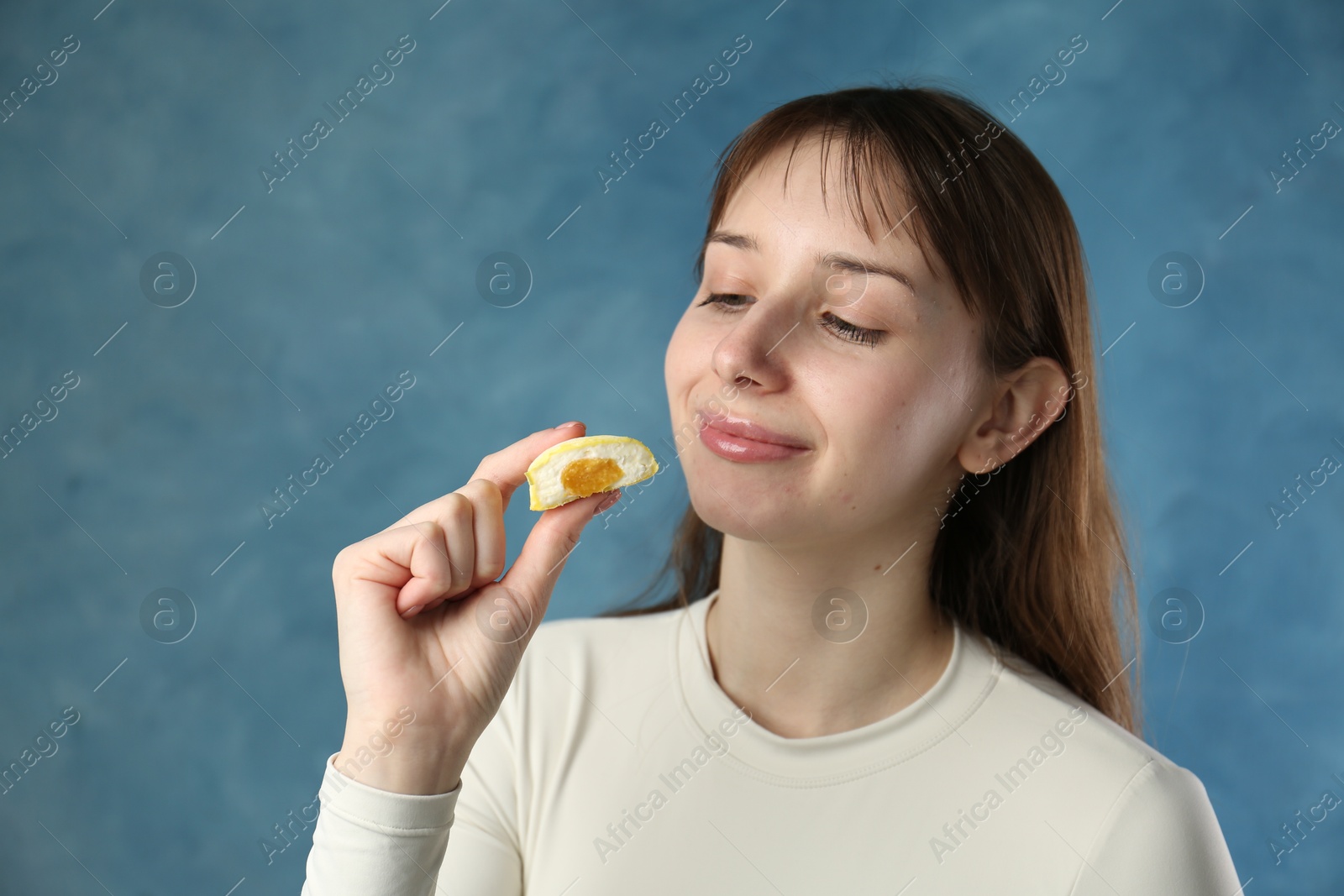 Photo of Beautiful woman with tasty mochi on blurred blue background