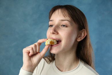 Photo of Beautiful woman eating tasty mochi on blurred blue background