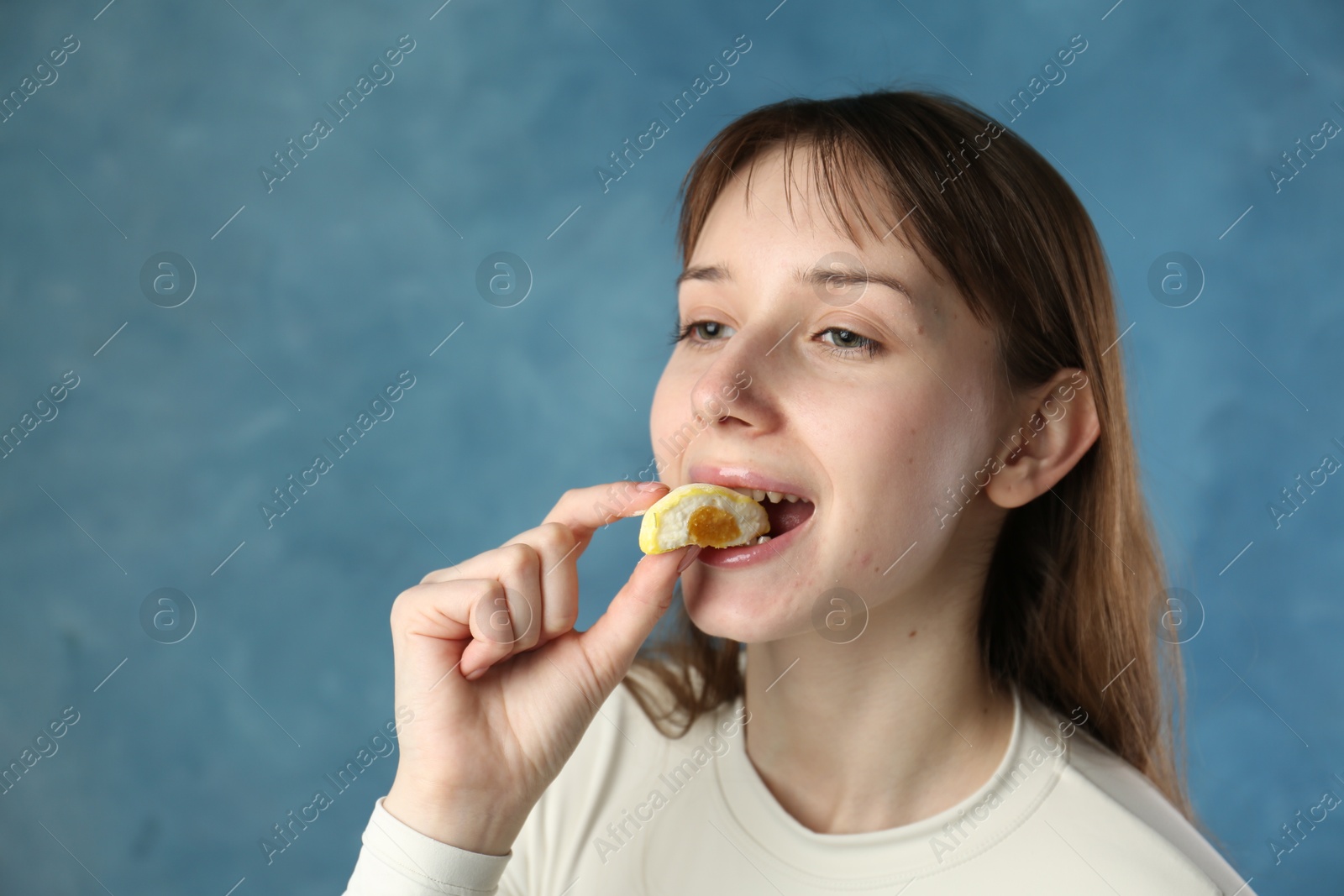 Photo of Beautiful woman eating tasty mochi on blurred blue background