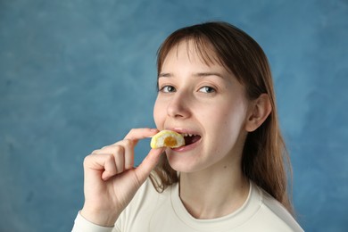 Photo of Beautiful woman eating tasty mochi on blurred blue background