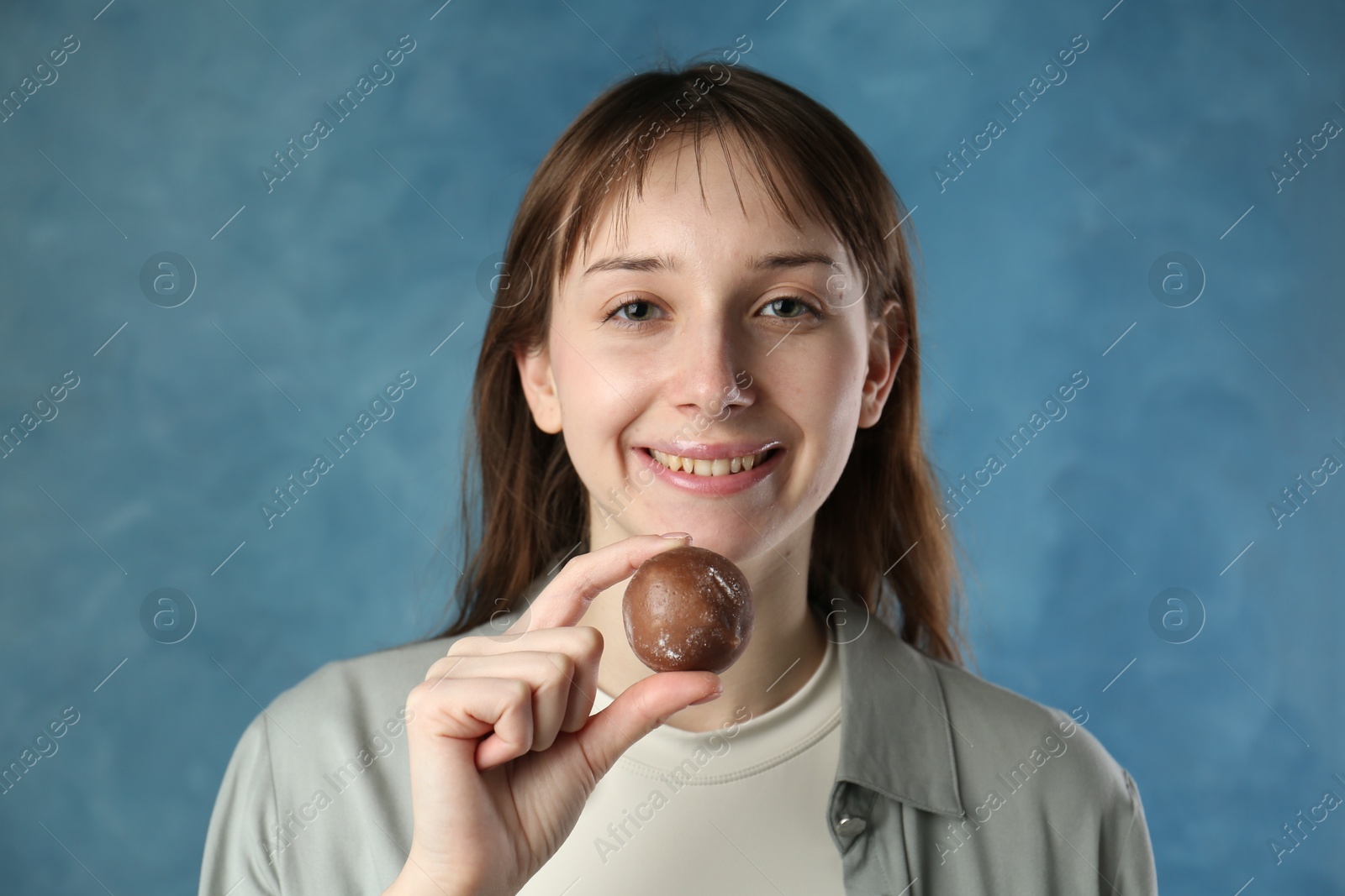 Photo of Smiling woman with tasty mochi on blurred blue background