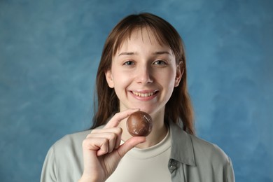 Photo of Smiling woman with tasty mochi on blurred blue background