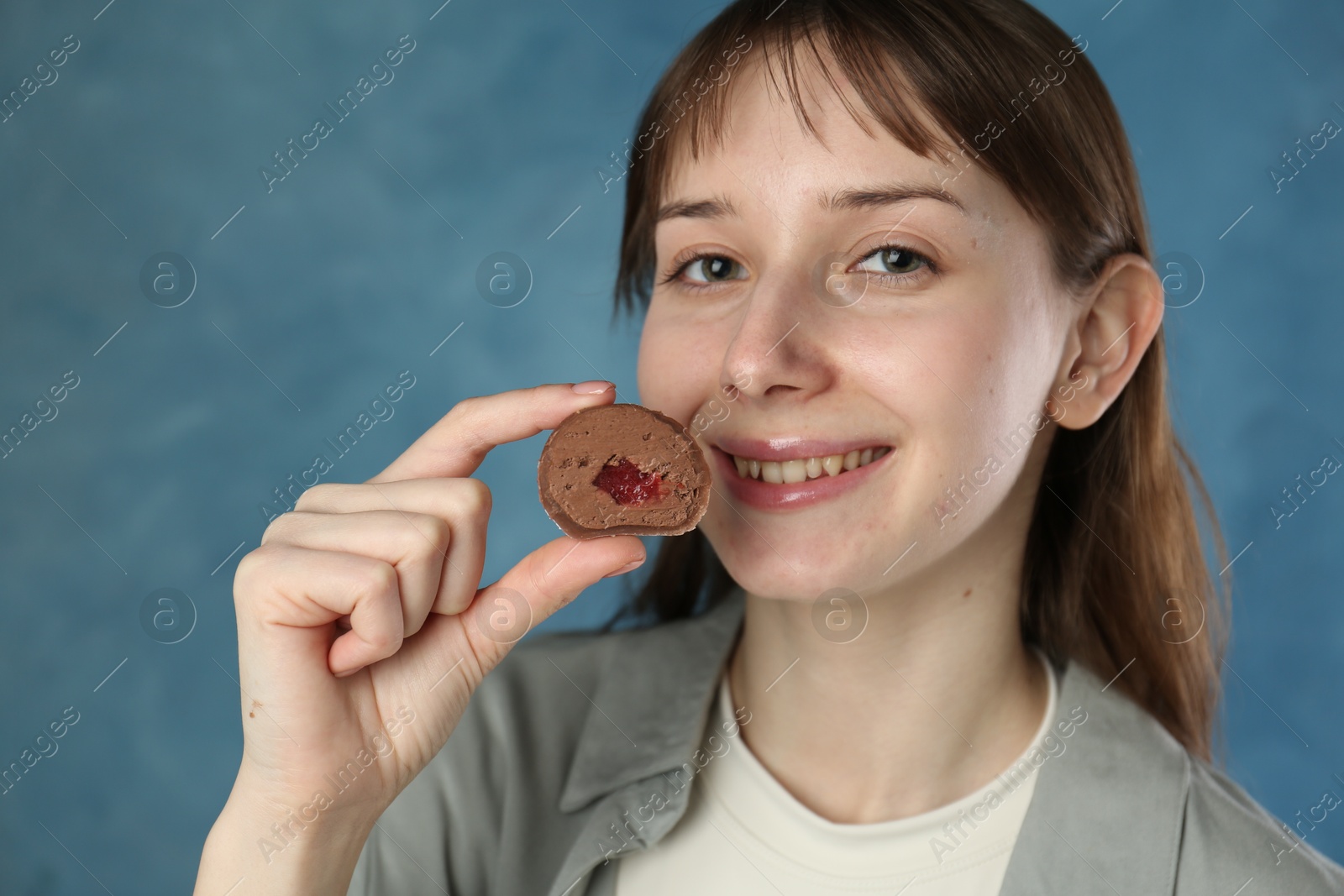 Photo of Smiling woman with tasty mochi on blurred blue background