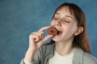 Photo of Beautiful woman eating tasty mochi on blurred blue background. Space for text