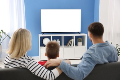 Photo of Happy family watching tv together at home, back view