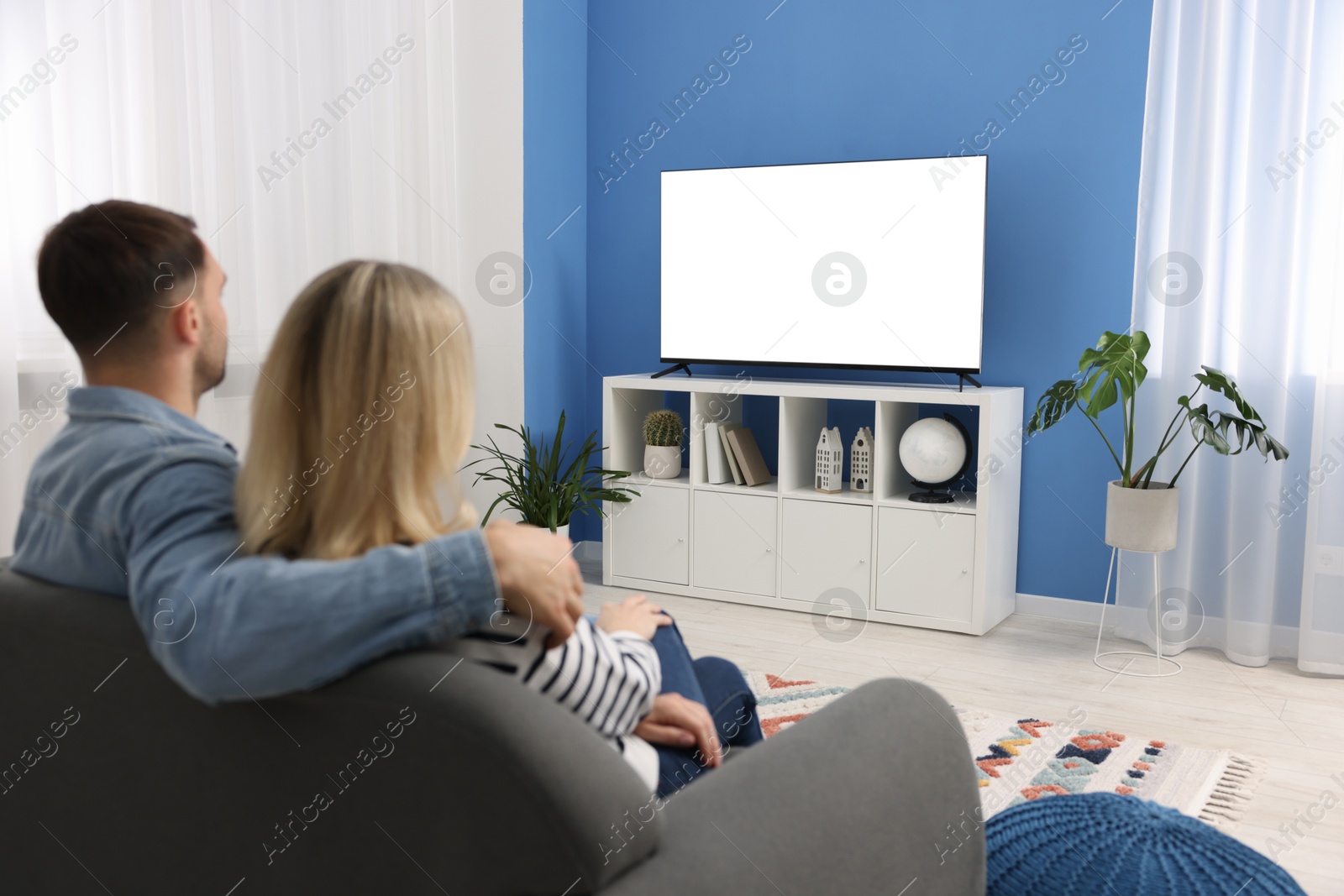 Photo of Lovely couple watching tv on couch at home