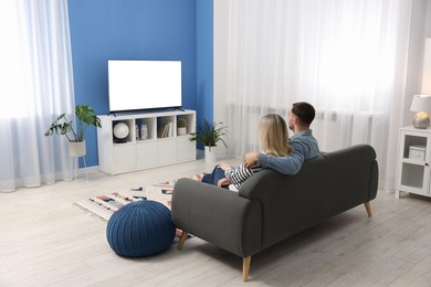 Photo of Lovely couple watching tv on couch at home