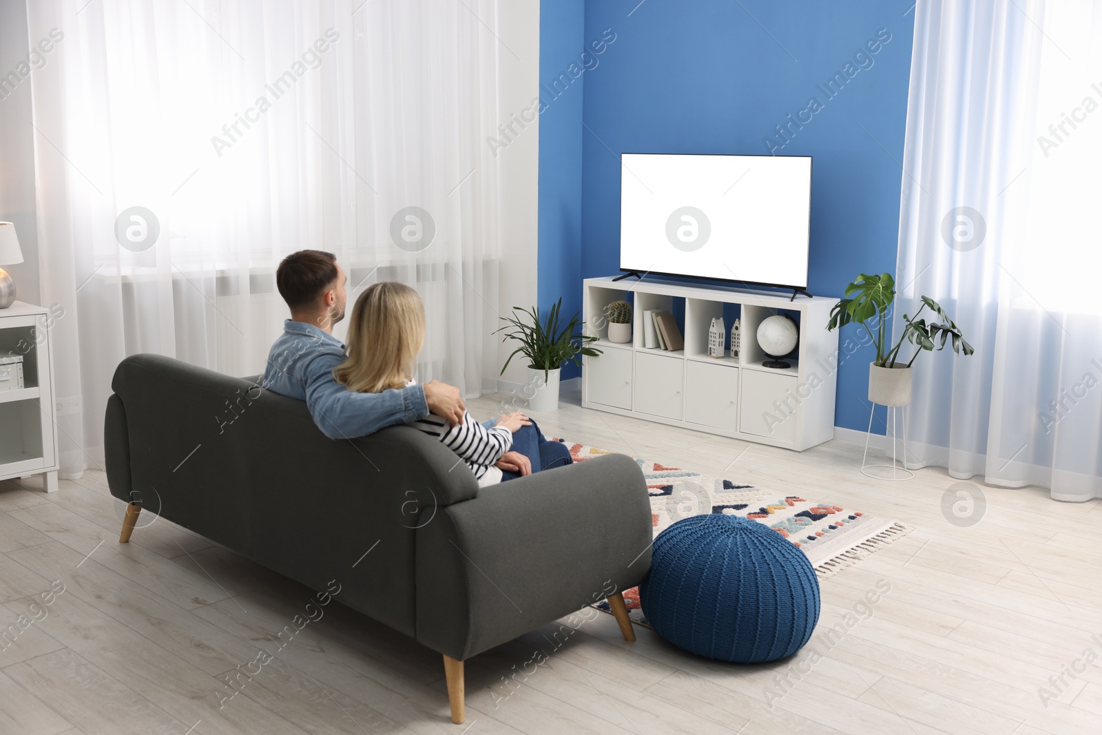 Photo of Lovely couple watching tv on couch at home