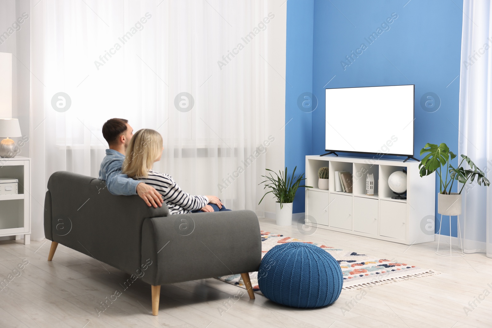 Photo of Lovely couple watching tv on couch at home