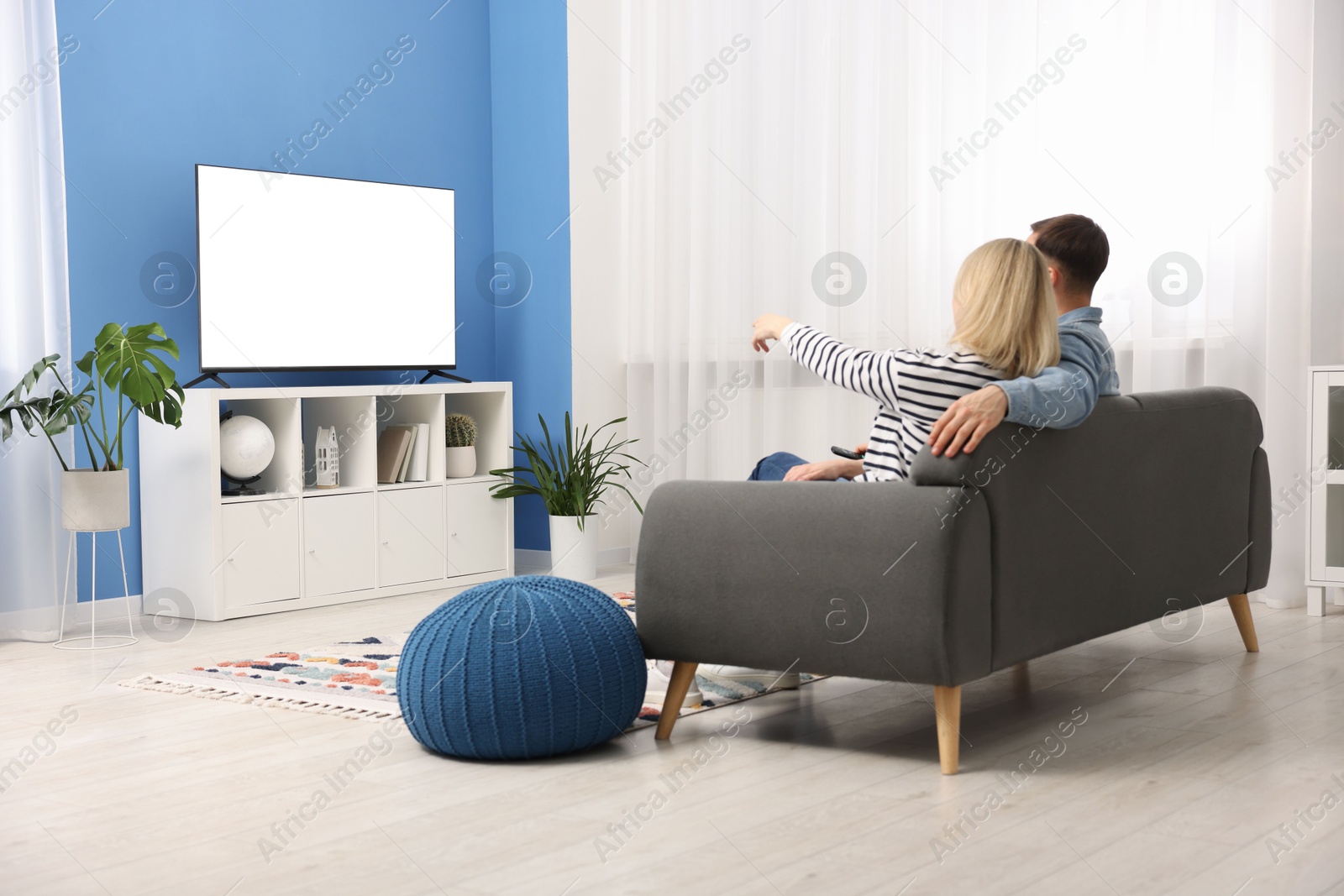 Photo of Lovely couple watching tv on couch at home