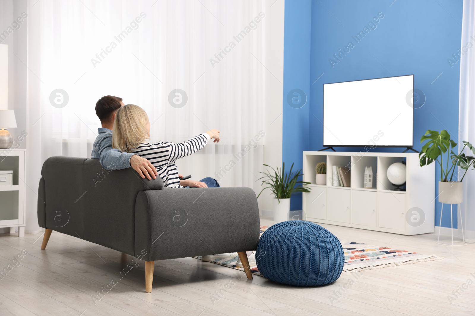 Photo of Lovely couple watching tv on couch at home