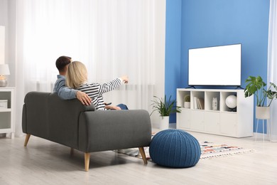 Photo of Lovely couple watching tv on couch at home