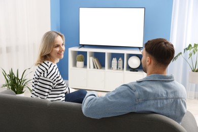 Photo of Lovely couple watching tv on couch at home