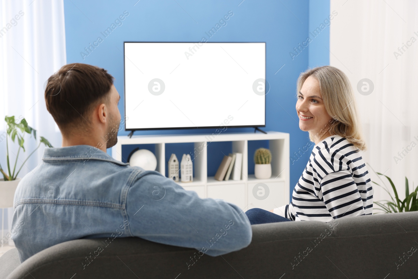 Photo of Lovely couple watching tv on couch at home