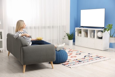 Photo of Woman with chips watching tv on couch at home