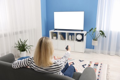 Photo of Woman watching tv on couch at home, back view