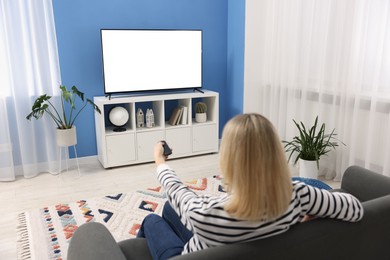 Photo of Woman watching tv on couch at home, back view