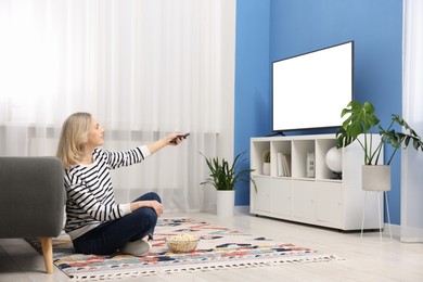 Photo of Woman with popcorn watching tv on floor at home