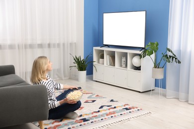 Photo of Woman with popcorn watching tv on floor at home