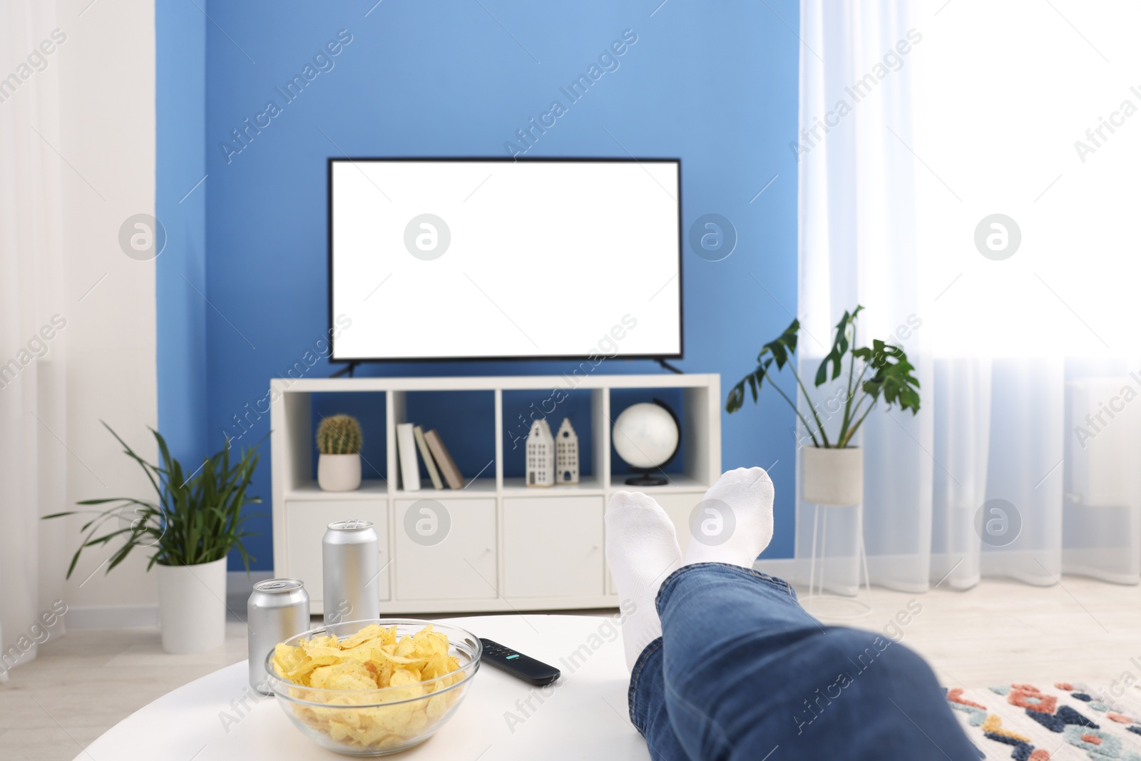 Photo of Woman with snacks and drinks watching tv at home, closeup