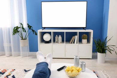 Photo of Woman with snacks and drinks watching tv at home, closeup