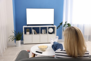 Photo of Woman watching tv on couch at home, back view