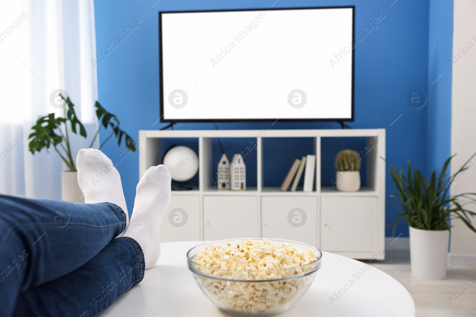 Photo of Woman with popcorn watching tv at home, closeup