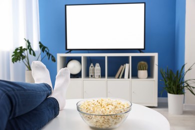 Photo of Woman with popcorn watching tv at home, closeup