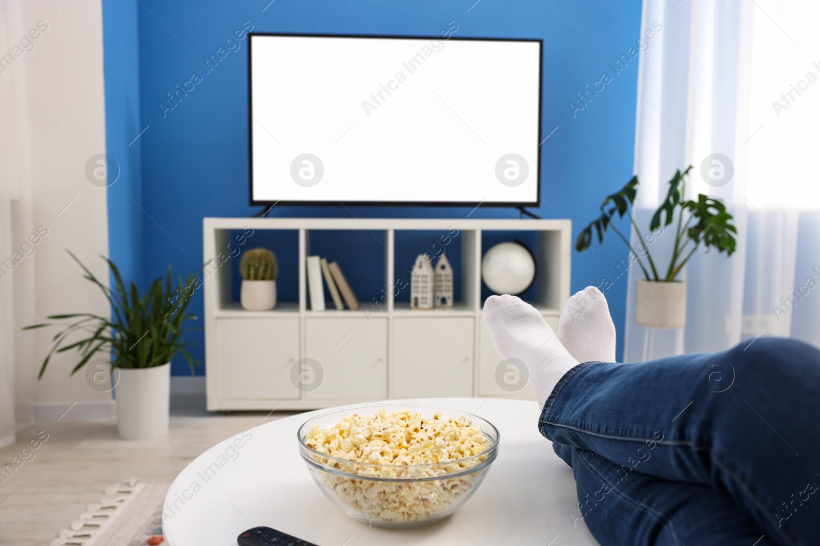 Photo of Woman with popcorn watching tv at home, closeup